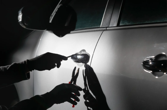 car thief using tools to break into a car