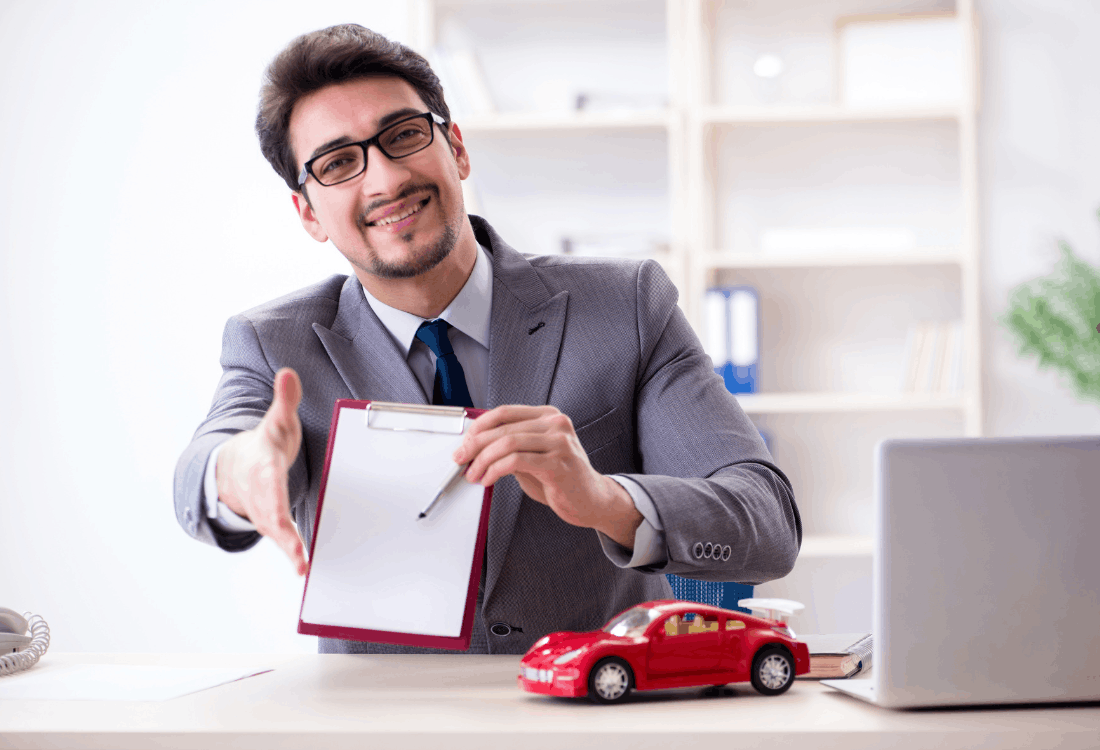 A man working in a motor trade company handing out papers that need to be signed to future customers.