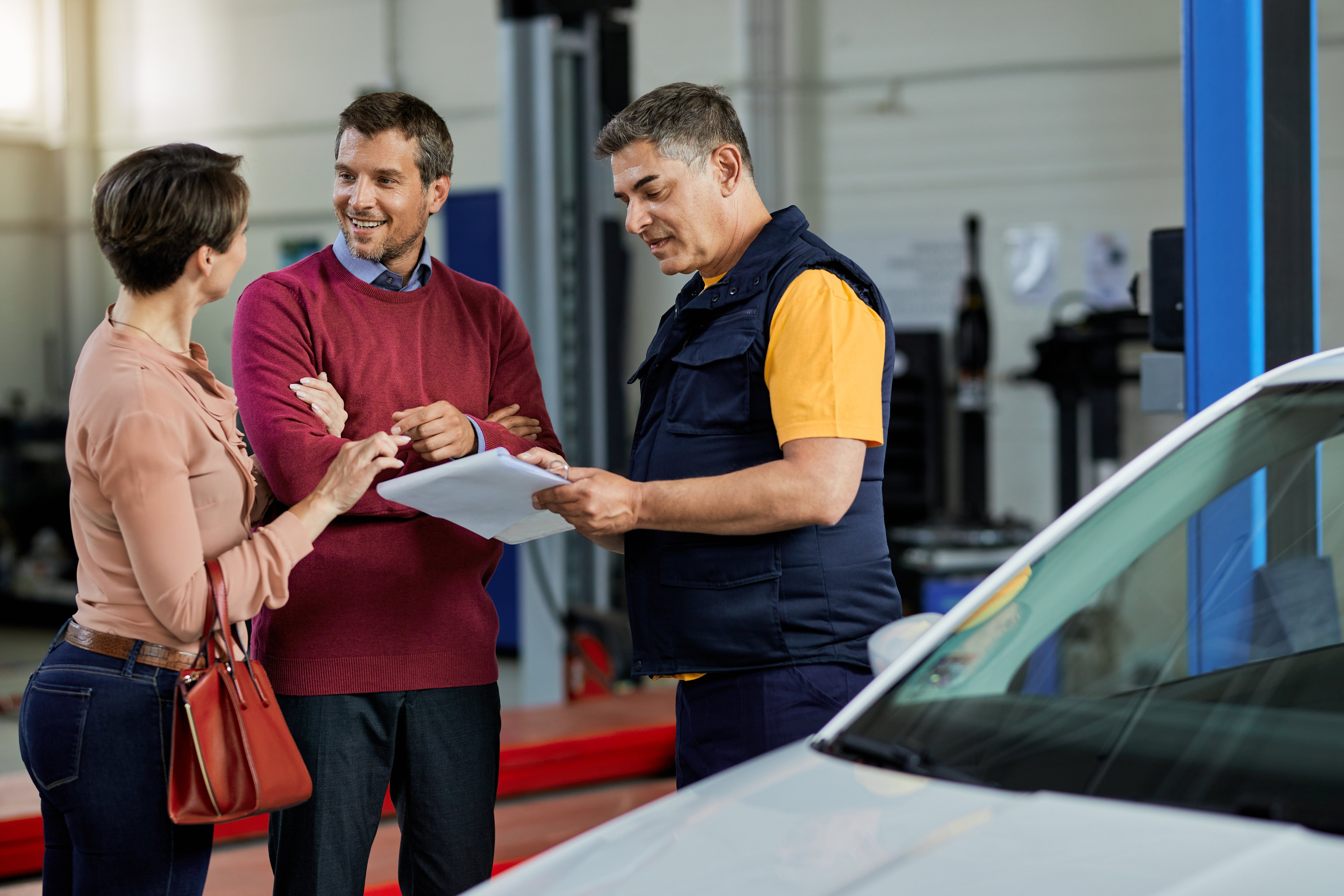Customer discussing motor trade insurance policy options with a vehicle service advisor in a garage.